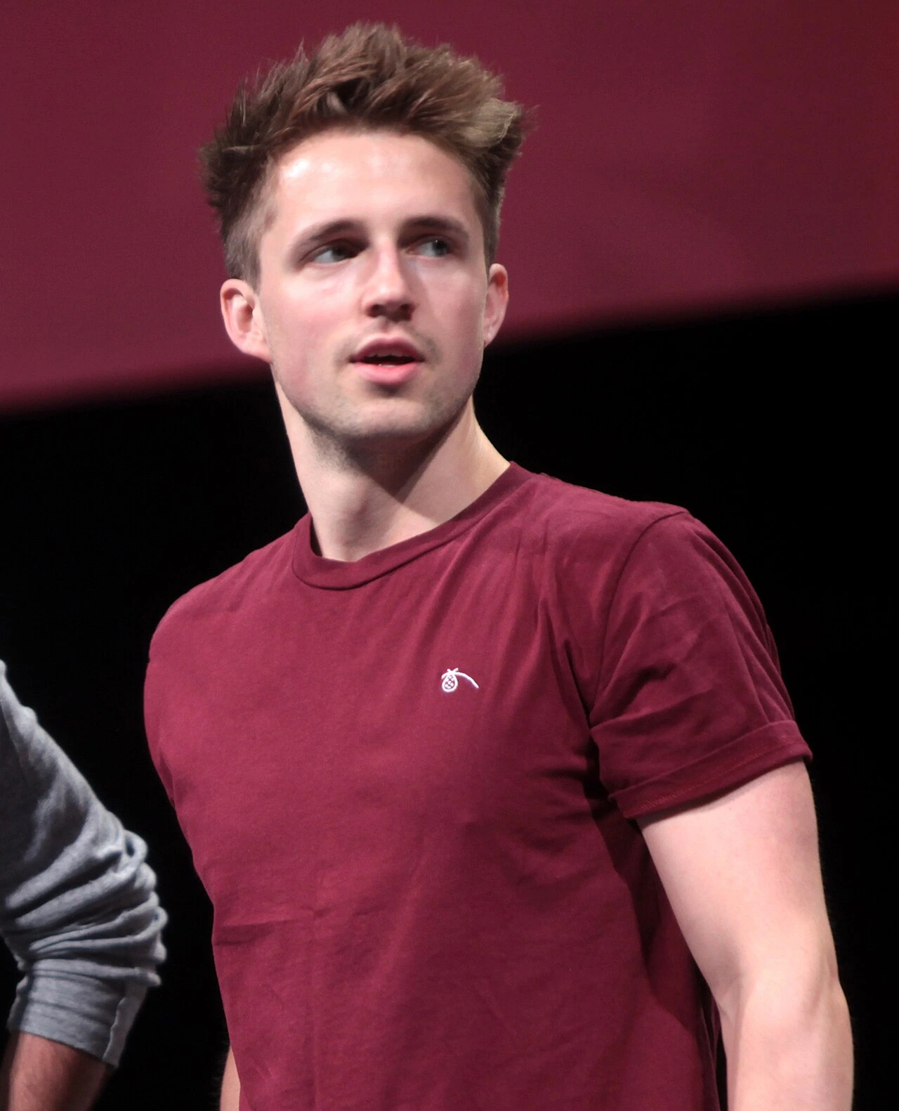 Marcus Butler at an event, wearing a maroon shirt and looking to the side